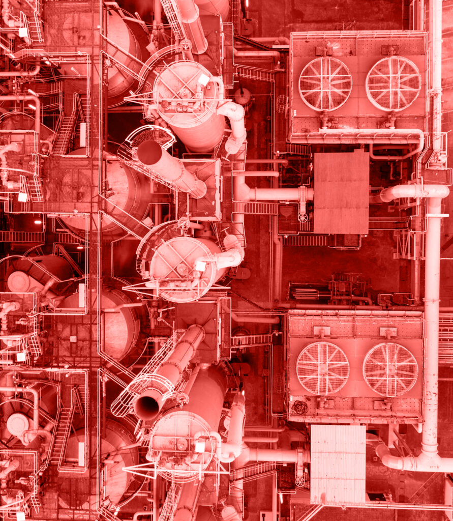 Aerial view of an industrial facility with large tanks, pipes, and cooling fans, displayed with a red color overlay.