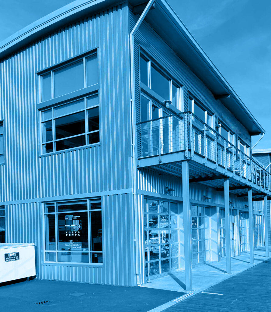 Modern industrial building with large windows, metal siding, and an upper-level balcony, shown with a blue color overlay